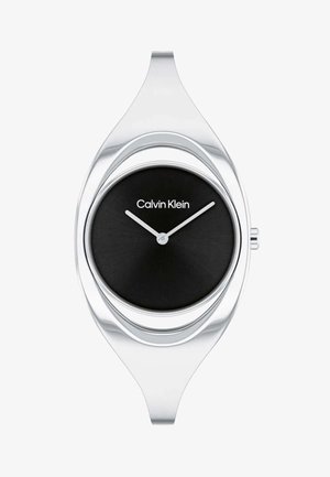 Montre argentée avec un boîtier ovale élégant et un cadran minimaliste noir. Dispose d'aiguilles des heures et des minutes blanches et du logo "Calvin Klein".