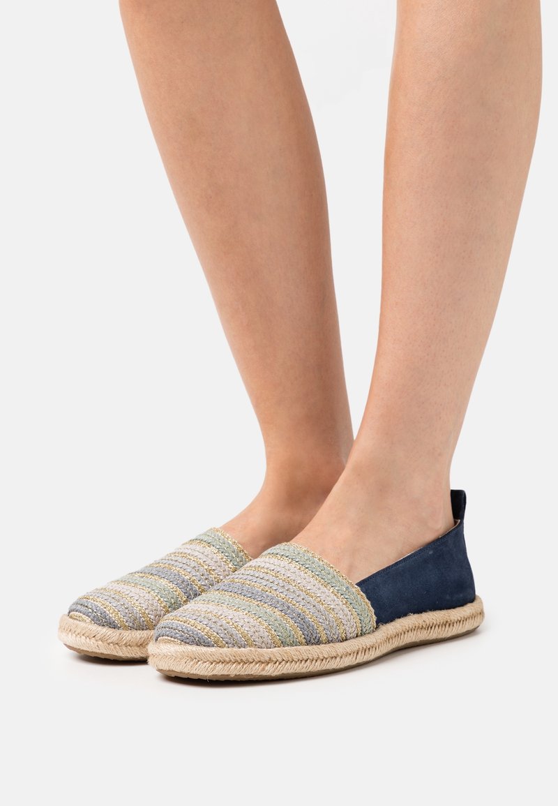 Chaussures en toile à enfiler présentant un motif tissé en tons bleu clair et vert, avec un talon uni bleu marine et des semelles en jute pour la texture.