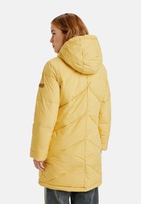 Geel pufferjack met een capuchon, voorzien van een geblokt ontwerp en zijzakken. De stof is soepel en glanzend, met een ontspannen pasvorm.