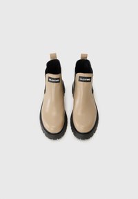 Botas de tobillo de goma beige con acentos negros, con una suela texturizada y lengüetas de tira, marcadas con "VALENTINO" en los paneles laterales.