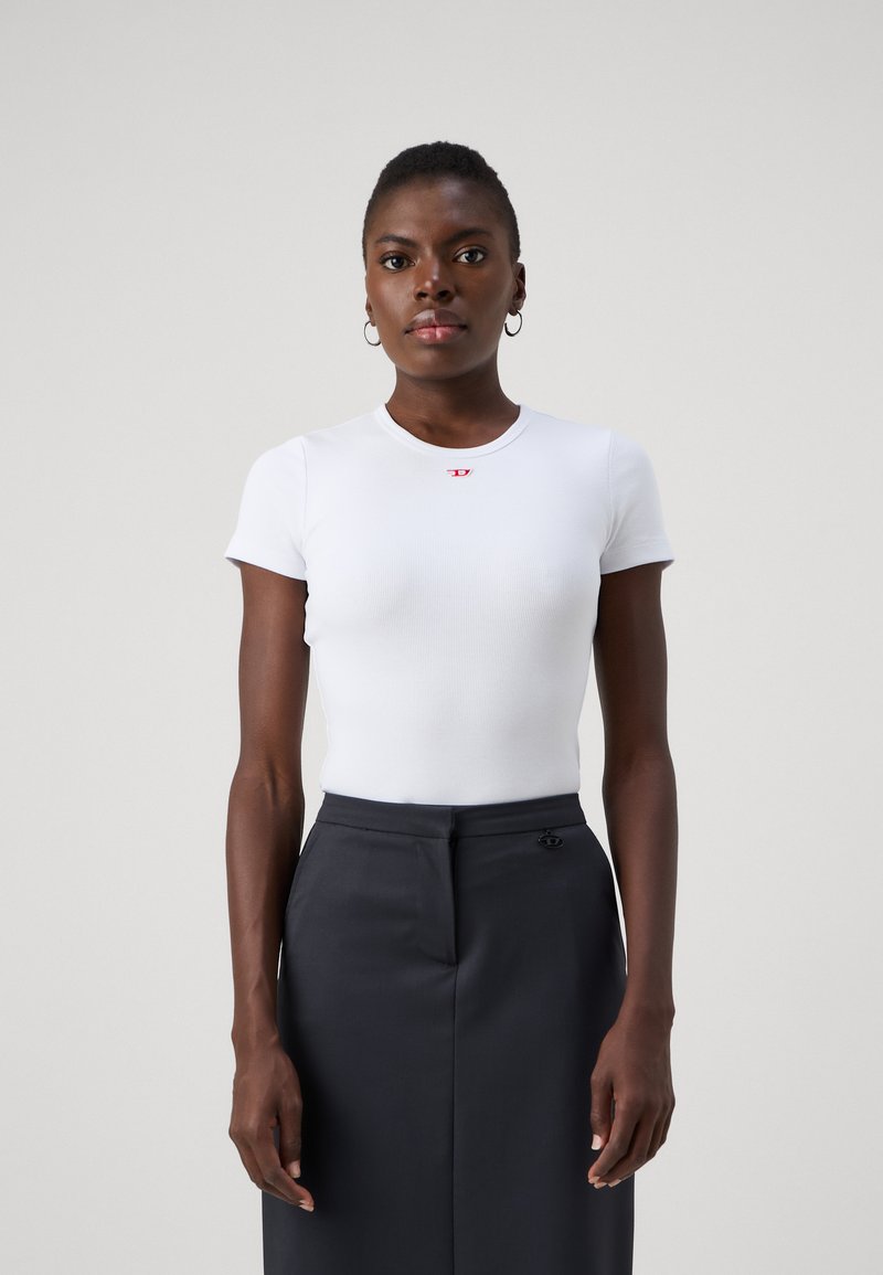 White ribbed short-sleeve top with a round neckline and small red logo; paired with a fitted dark gray skirt featuring subtle hardware detail.