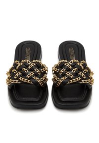 Sandales à glissière en cuir noir avec bouts carrés et brides tressées ornées de maillons de chaîne dorés.