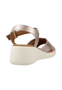 Sandal in metallo oro con apertura sulle dita, caratterizzato da un design con fasce morbide, soletta imbottita e una spessa suola in gomma bianca per una maggiore stabilità.