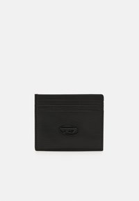 Tarjetero de cuero negro con un acabado texturizado, que cuenta con cuatro ranuras para tarjetas y un acento del logotipo en el centro. Diseño compacto con líneas limpias.