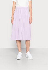 Lila midi rok van zacht materiaal, met een elastische tailleband en plooien, in combinatie met witte platform sneakers voor een casual uitstraling.