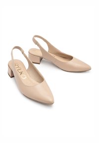 Kreminės odinės slingback bateliai su smailiu pirštu, žemu blokiniu kulnu ir išpjovomis šoninėse dalyse. Aukso spalvos ženklas matomas ant pado.