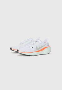 Baskets de sport en maille blanche avec des accents argentés, des détails orange sur la semelle et une semelle extérieure en caoutchouc noir ; conception à lacets avec un col rembourré.