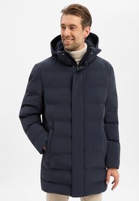 Marineblauwe donsjas met capuchon, voorzien van een ritssluiting en drukknoopsluiting, zijzakken en een doorgestikte structuur voor isolatie.