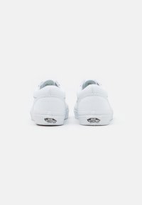 Hvide kanvas sneakers med lav profil, rund tå og gummisåler. Har et sort "Vans Off the Wall" logo på hælen.