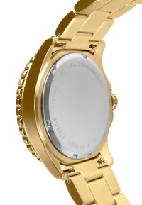 Montre en acier inoxydable doré avec un boîtier rond et plat et un bracelet à maillons. Le dos présente des gravures. Extérieur lisse et poli avec une finition brillante.