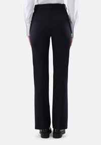 Schwarze weit geschnittene Hose mit glatter Textur, hoher Taille und dezenten Nahtdetails auf der Rückseite. Die Hose ist mit schwarzen Schuhen auf einem schlichten Hintergrund kombiniert.