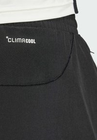Schwarze Sportshorts mit glatter Textur, die ein weißes CLIMACOOL-Logo und kontrastierende Nahtdetails im Bereich der Tasche aufweisen.