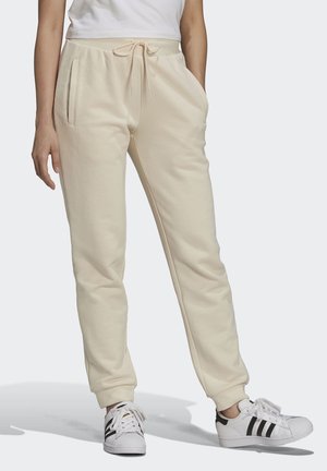 Pantalones de chándal beige hechos de tela suave, con una cinturilla ajustable con cordón, dos bolsillos laterales y puños ajustados en los tobillos.