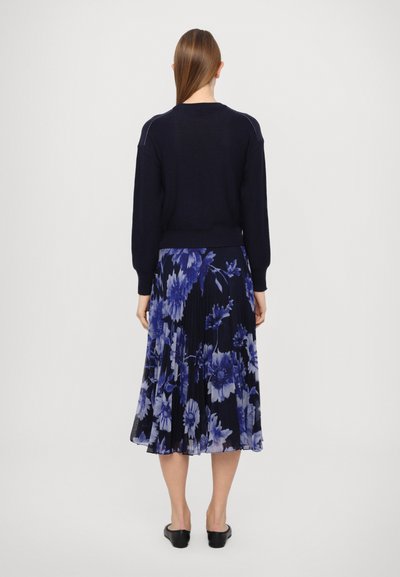 Navy sweater with long sleeves, paired with a pleated floral skirt in blue and purple tones. Smooth texture and casual silhouette.