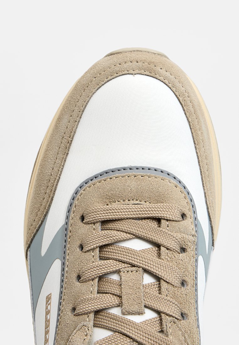 Sneaker mit einem Obermaterial aus beigem Wildleder und weißem Stoff, grauen Akzenten und einer strukturierten Gummisohle. Mit flachen Schnürsenkeln und einer genähten Zehenkappe.