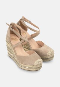 Zeppe espadrillas beige con tomaia in tela, cinturini alla caviglia, punta aperta e dettagli in juta intrecciata. Presenta un accento metallico decorativo.