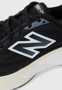 Close-up of black New Balance sneaker with white and gray "N" logo and Fresh Foam label on tongue.