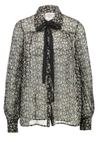 Blouse noire transparente avec petit imprimé floral blanc, manches longues bouffantes, fermeture à boutons sur le devant et un nœud en ruban noir noué au col.