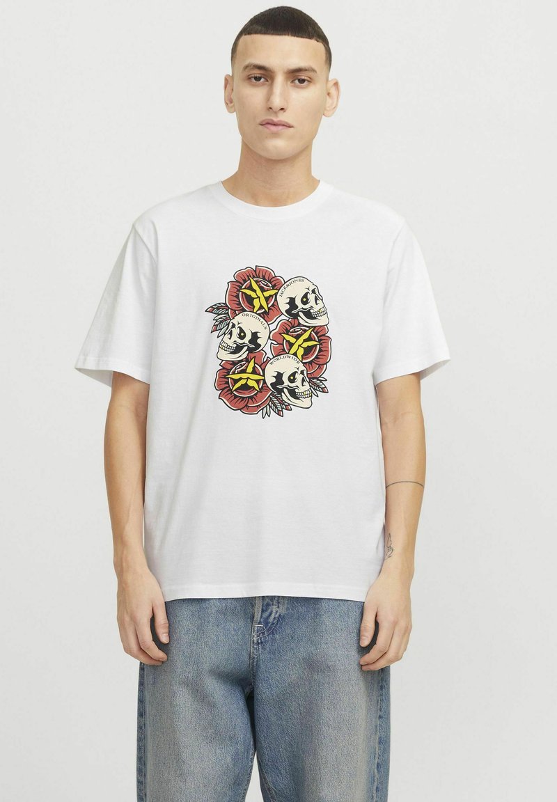 Hvid bomulds t-shirt med et centralt motiv af fire kranier omgivet af røde blomster og gule stjerner. Løs pasform og korte ærmer.