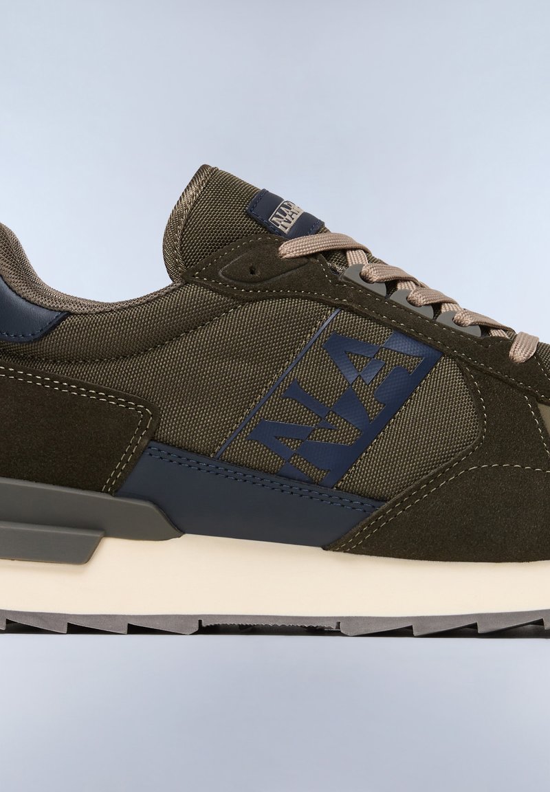 Zielono-oliwkowy tenisówki z teksturowanym materiałem i gładkimi zamszowymi akcentami, z granatowym logo, beżowymi sznurówkami i białą podeszwą środkową.