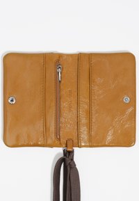 Wnętrze skórzanego portfela w kolorze brązowym, z zamykaną kieszonką, wieloma miejscami na karty oraz ciemnobrązowym materiałowym paskiem zawiązanym w supeł. Gładka, błyszcząca tekstura.