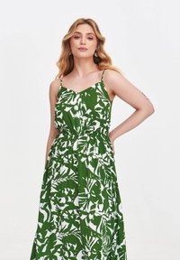 Grünes und weißes Maxikleid mit floralem Muster, verfügt über dünne Träger und einen elastischen Bund für eine lockere Passform. Glattes, leichtes Material.