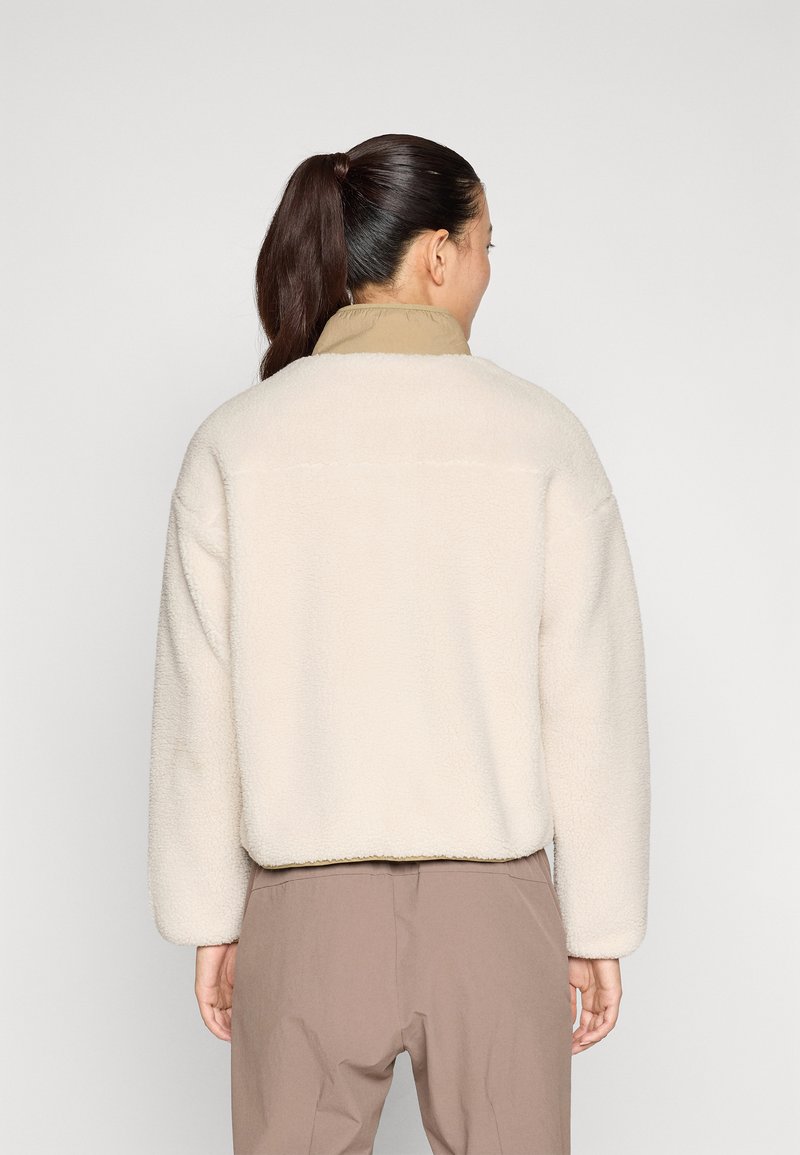 Giacca in pile color crema con colletto beige. Design oversized, texture morbida e spalle scese. Tessuto liscio e vestibilità rilassata.