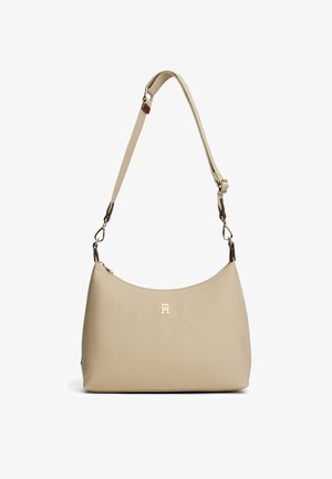 Borsa in pelle beige con una texture liscia, forma arrotondata, tracolla regolabile e logo dorato sul davanti. Adatta per un uso quotidiano.