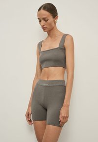Szürke bordázott crop top vastag pántokkal és hozzá illő, magasderekú sorttal. Az anyag puha tapintású. A derékpánton logó található.