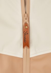Cream and tan waterproof jacket with a smooth texture, featuring a front zipper and a leather pull tag labeled "Stentler."