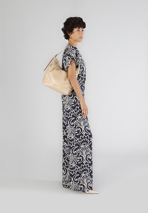 Abito lungo con base blu navy e motivo floreale bianco; maniche corte. La modella porta una borsa in pelle beige con dettagli intagliati e una texture liscia.