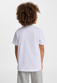 Vitt bomull t-shirt med korta ärmar och rund halsringning, enkel design, med en avslappnad passform och slät textur. Bakifrån.