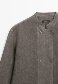 Grijze linnen koksbuis met een mandarin kraag en een dubbelrijig ontwerp met vier knopen.