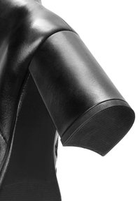 Zwarte leren schoen met een ronde hak en een getextureerde rubberen onderzijde. Het ontwerp heeft gladde oppervlakken en strakke lijnen.