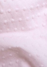 Tessuto rosa chiaro con una superficie testurizzata caratterizzata da punti in rilievo, che conferisce una qualità morbida e tattile. Il materiale appare liscio e lavorato a maglia.
