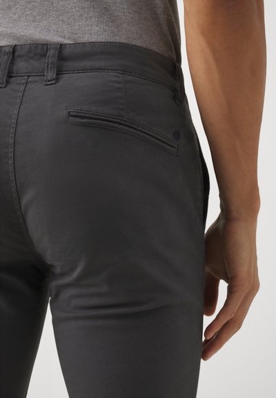Pantalons slim gris foncé avec une texture lisse, dotés d'une poche arrière et de passants de ceinture. Le tissu semble léger et polyvalent.
