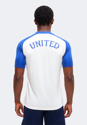 Uomo che indossa una camicia bianca e blu a maniche corte con la scritta "UNITED" stampata in blu sulla parte superiore della schiena.