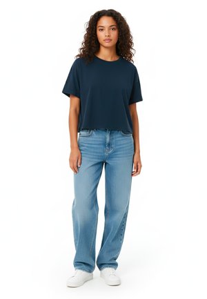Marineblauw crop t-shirt met korte mouwen, gecombineerd met lichtblauwe wijde jeans en witte sneakers; casual pasvorm en een gladde textuur.