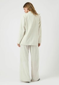 Lichtgekleurde krijtstreep pak gemaakt van gestructureerde stof, met een lange blazer en wijde broekspijpen, met een relaxed fit en minimale detaillering.