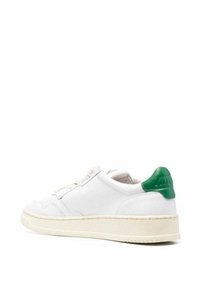 Sneaker bianco in pelle con superficie testurizzata, caratterizzato da un accento verde al tallone e una suola in gomma spessa. Design classico con lacci.