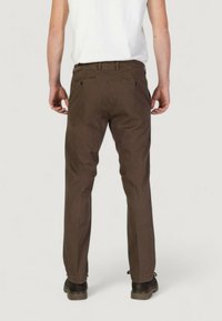 Pantaloni in cotone marroni con taglio dritto, dotati di tasche posteriori e passanti per la cintura. Tessuto texturizzato, abbinati a calzature scure.
