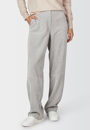 Person wearing light grey vertically striped wide-leg pants with side pockets, paired with white sneakers and a beige sweater.