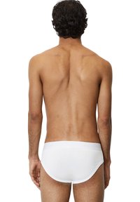 Weiße Baumwollslips mit einem weichen Bündchen, das ein eingeprägtes Logo trägt. Schlankes, minimalistisches Design betont Einfachheit und Komfort.