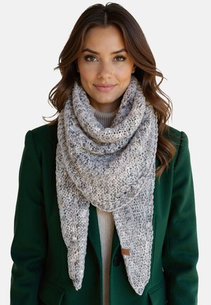 Strik scarf i nuancer af grå med et struktureret mønster, triangulær form og frynsede kanter, båret over en cremet sweater og en grøn frakke.
