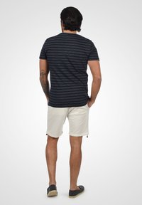 Marine gestreept T-shirt met korte mouwen, gecombineerd met lichtbeige shorts. Het shirt heeft een ronde hals en een slim fit ontwerp.