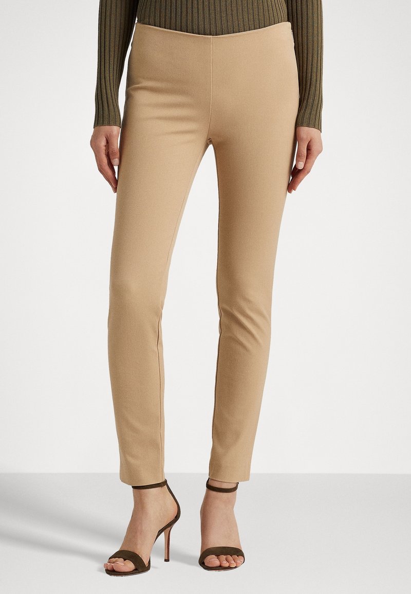 Tan färgade tighta byxor med en slät textur, som har hög midja och raka ben, i kombination med bruna klacksandaler.