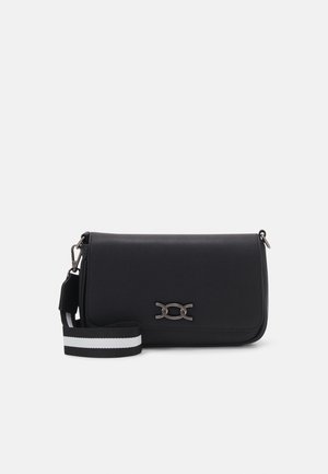 Black rectangular crossbody bag with silver clasp and detachable black and white striped shoulder strap on light background.