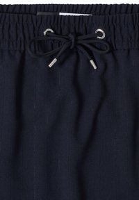 Pantalon bleu marine avec taille élastique et cordon noir noué en un nœud avec des embouts et œillets métalliques argentés.