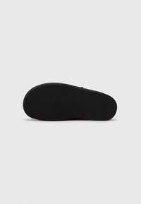 Semelle de chaussure noire avec surface texturée ; forme plate et bords arrondis ; faite en caoutchouc et conçue pour l'adhérence et la durabilité.