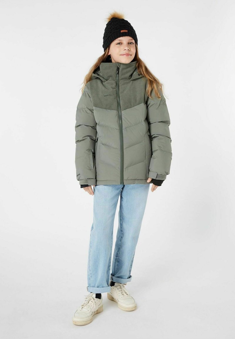 Giacca imbottita verde oliva con tessuto testurizzato, chiusura con zip e colletto alto. Abbinata a jeans azzurri chiari e sneakers bianche.